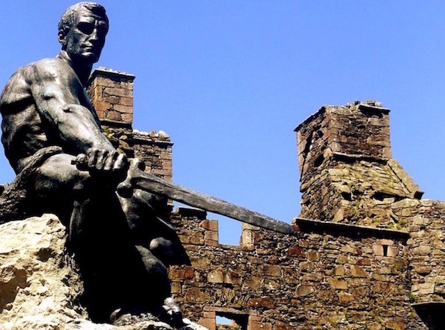 Statue of a seated man with a sword in front of MacLellan's Castle in Kirkcudbright