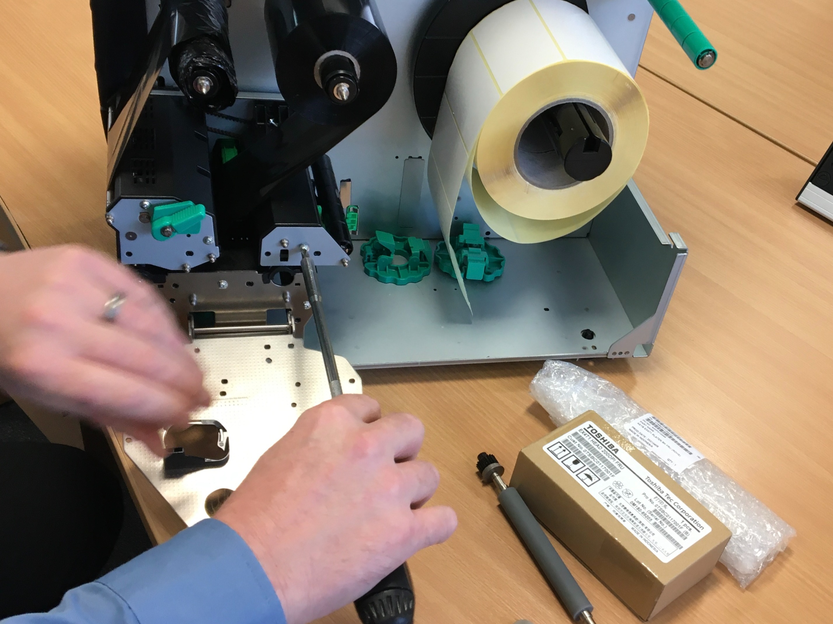 Printer engineer fitting new parts to a broken thermal printer