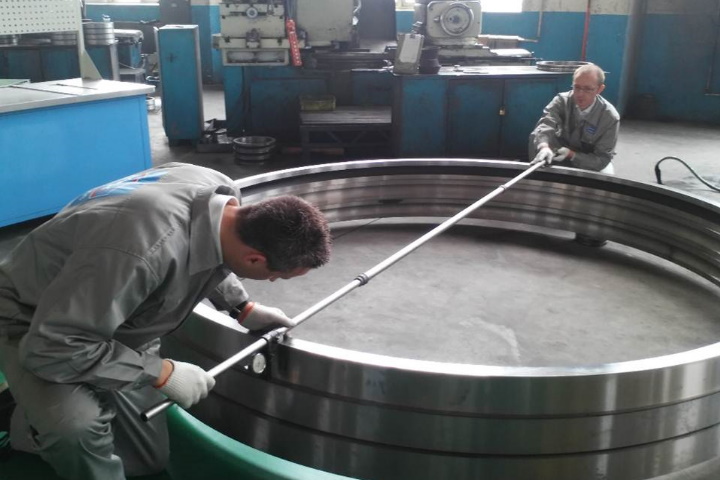 Two technicians measuring large bearing race