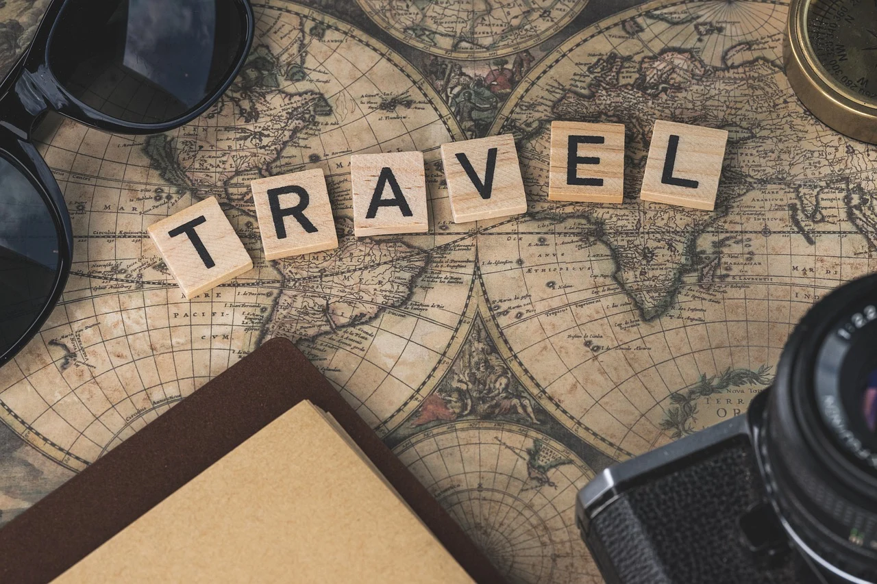 Travel spelled in scrabble-like wooden blocks on an old world map.