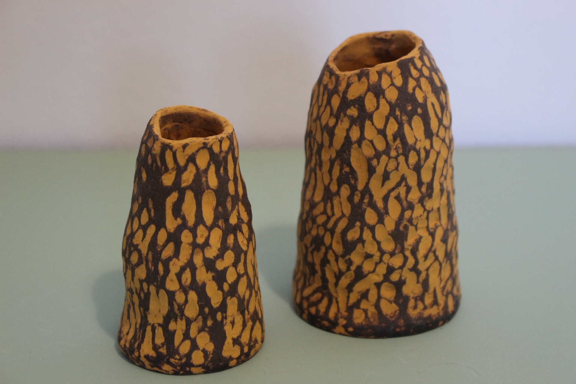 Two small choc brown clay vases with orange glaze
