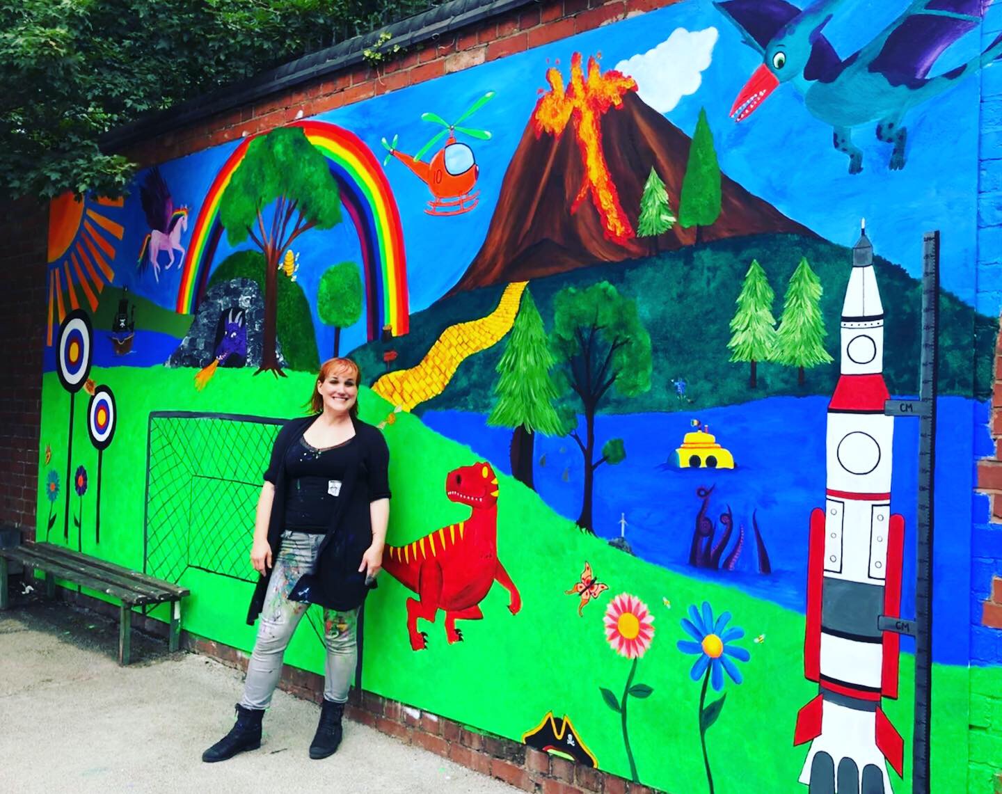 Mural Artist Rachel Akers of Akers of Art standing by the finished Mural at Harborne Primary School
