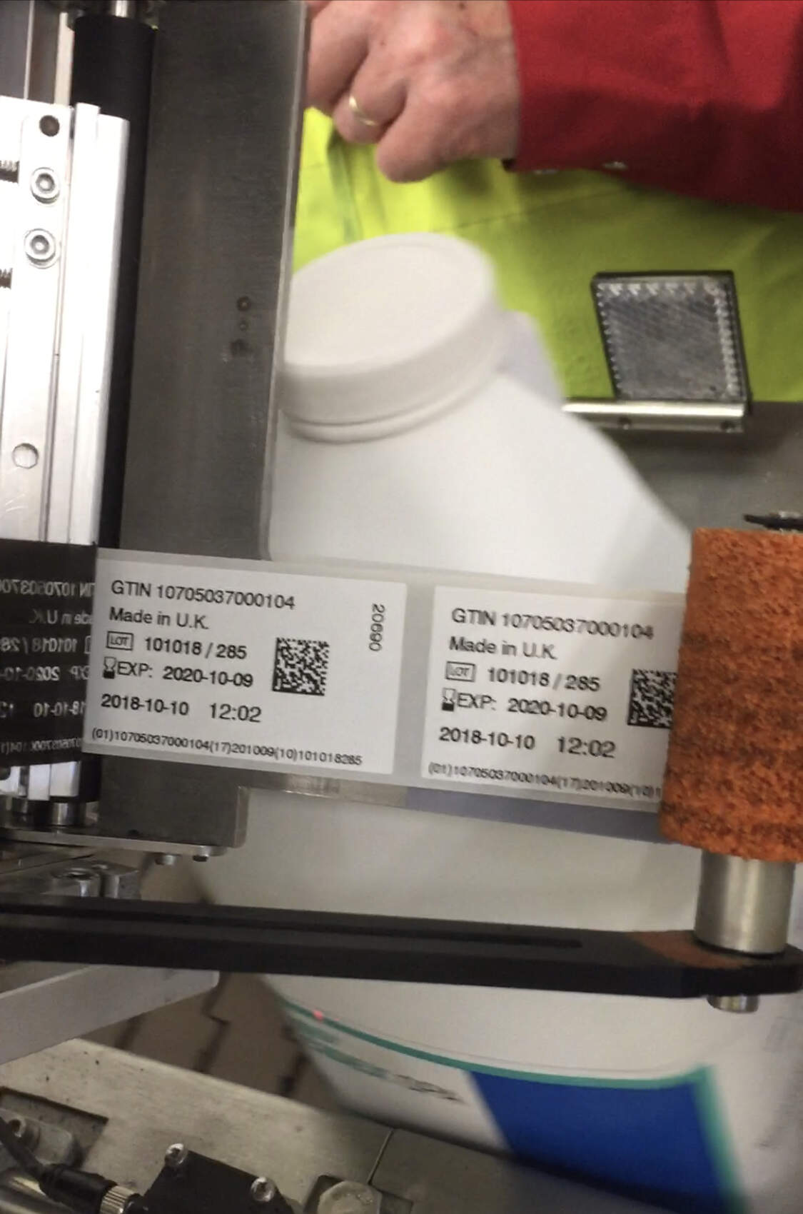 a print and apply machine applying labels to bottles on a conveyor belt