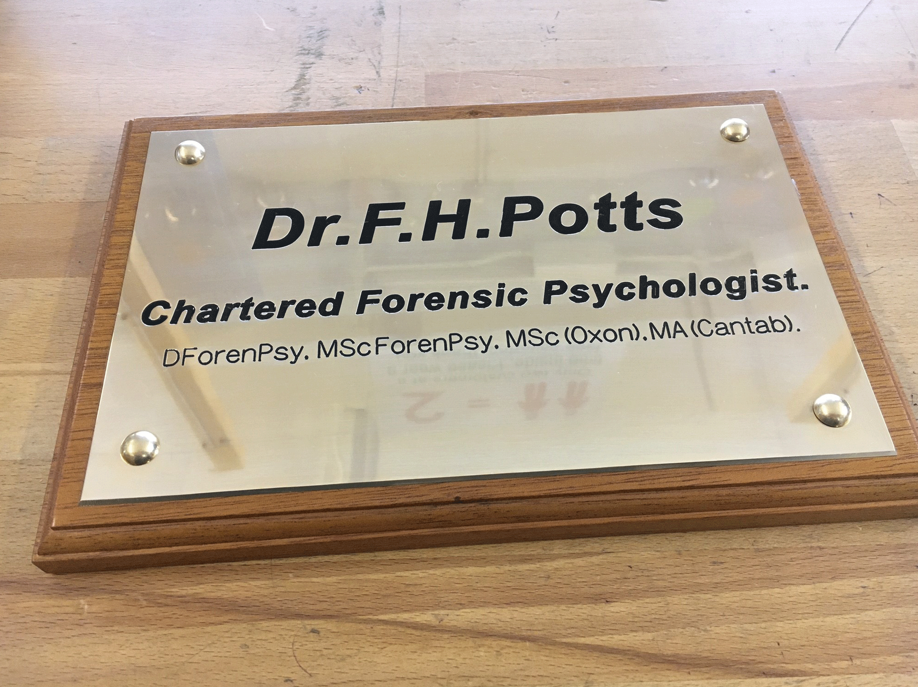 brass plaque engraved and filled black, mounted on light wood board