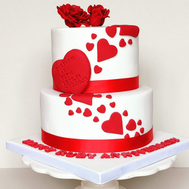 Anniversary cake decorated in red hearts and roses.