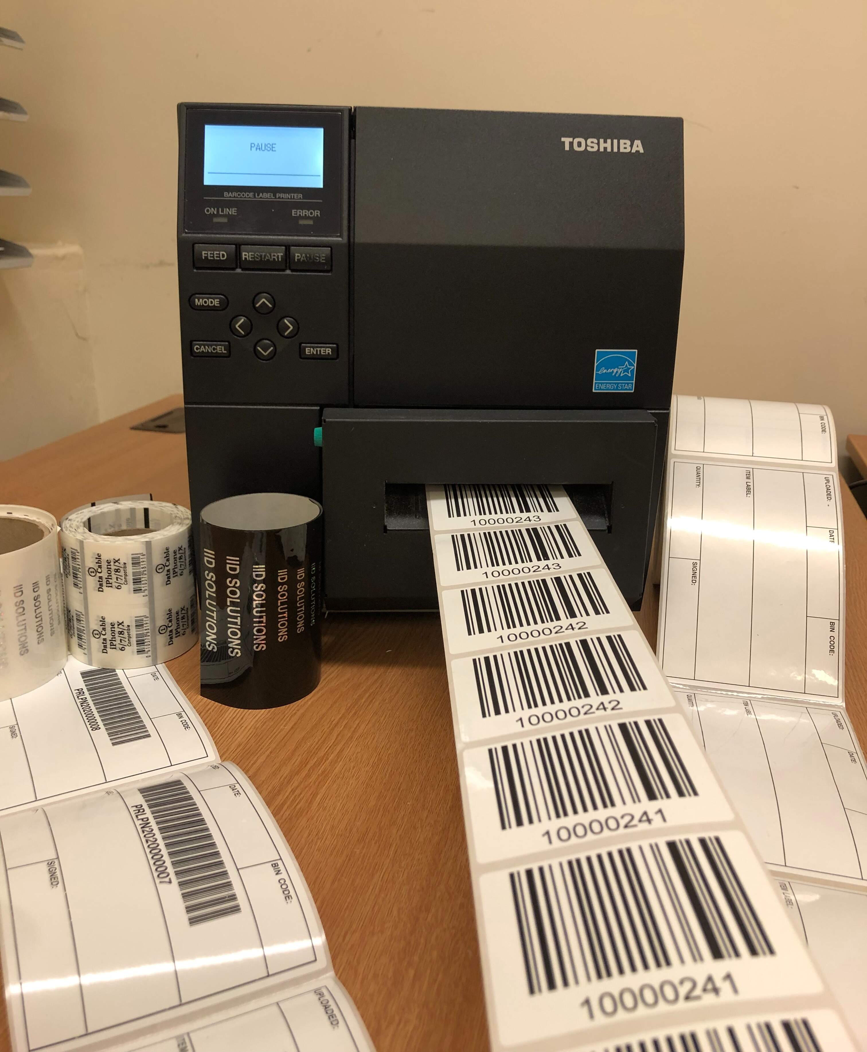 A thermal label printer printing urgent barcode labels with other rolls of printed labels by its side