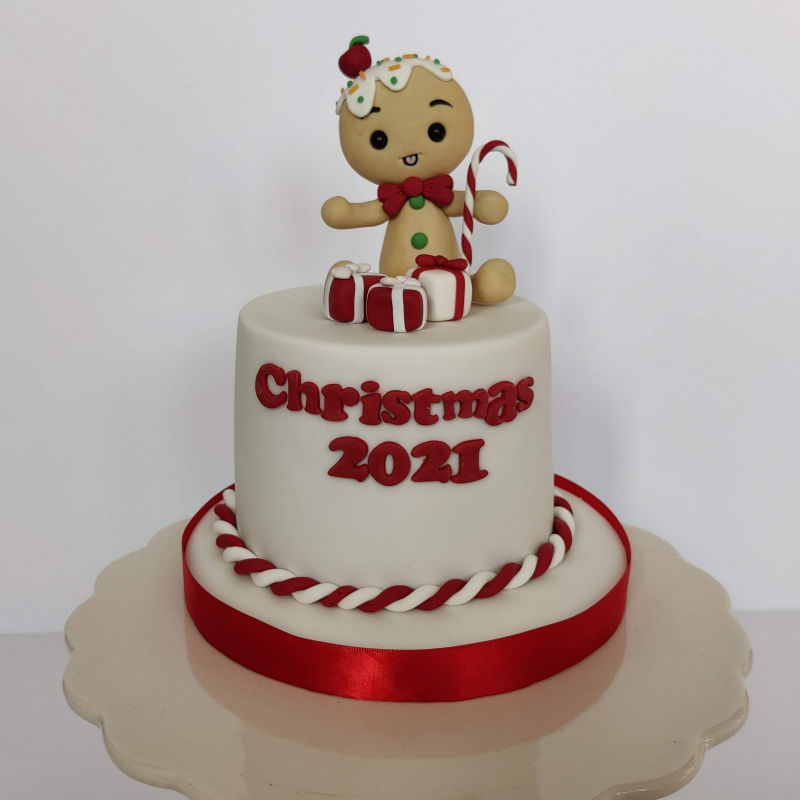 Christmas cake with gingerbread man topper and decorations.