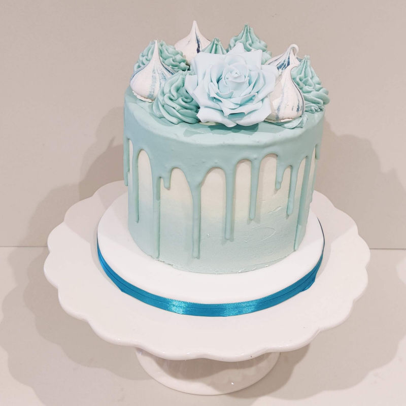 A Tiffany Blue drip cake with flowers and merringue kisses.