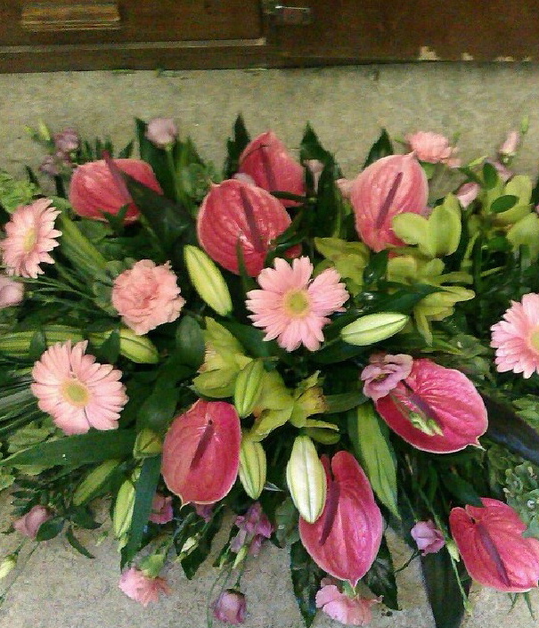 A funeral wreath from Flowers for You, Dalbeattie, using a mixture of green foliage, pink crysanthemums and pink calla lilies