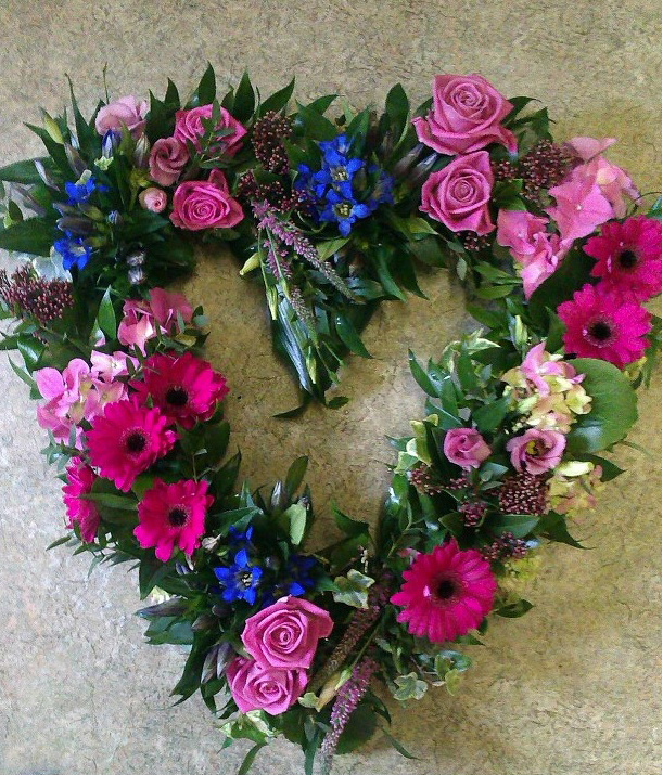 A funeral wreath from Flowers for You, Dalbeattie, using a large selection of flowers in varied colours, in a heart shape