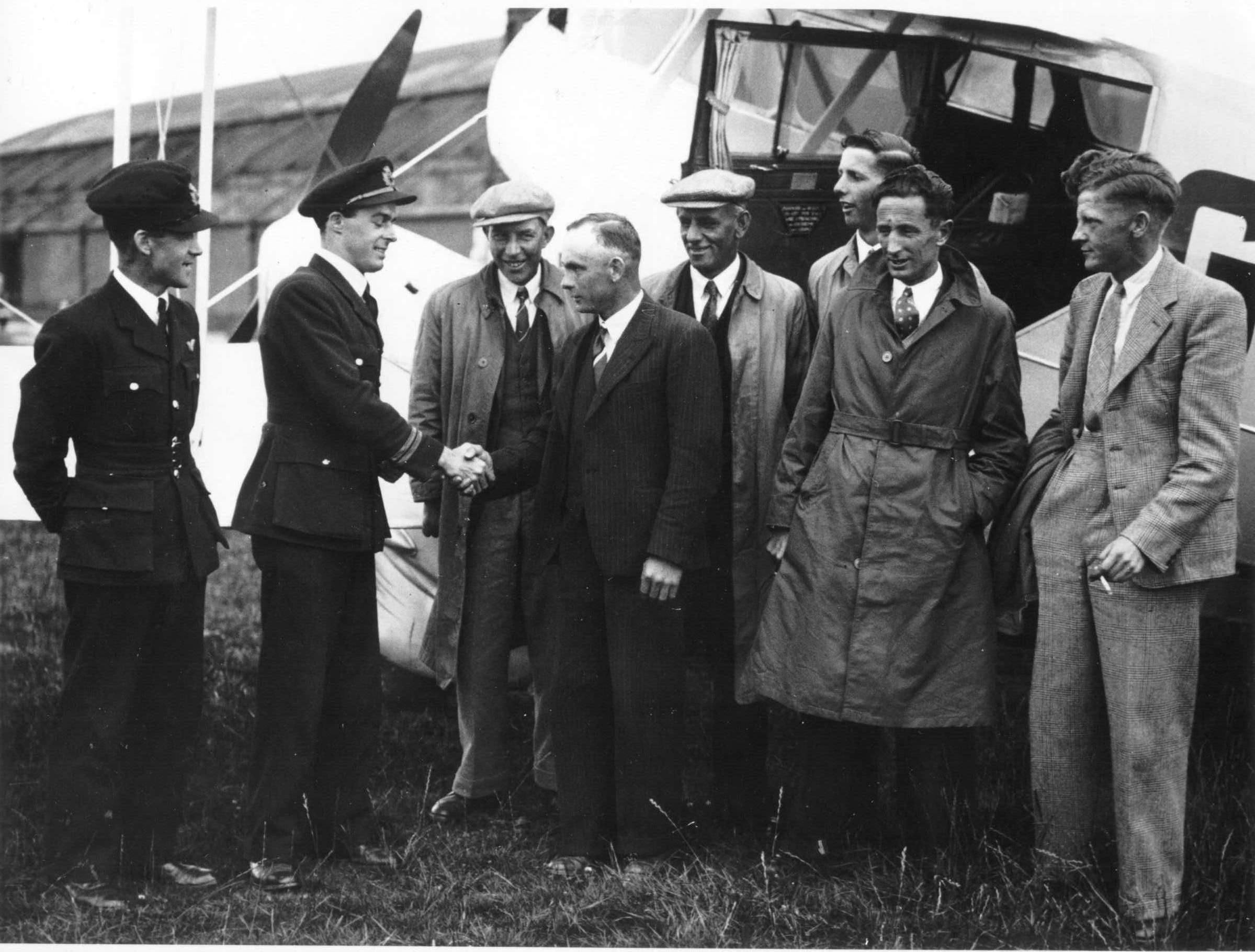 Two fligth crew with a group of local men in front of an aeroplane