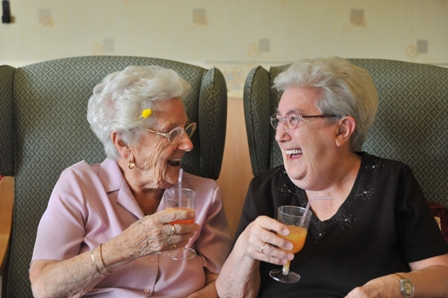 Two ladies laughing and enjoying a drink of orange juice