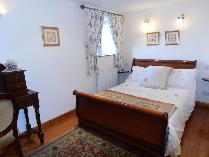 A double bed and other classic furniture adorn this beautiful double bedroom within The Dairy House self-catering holiday accommodation near Kirkcudbright